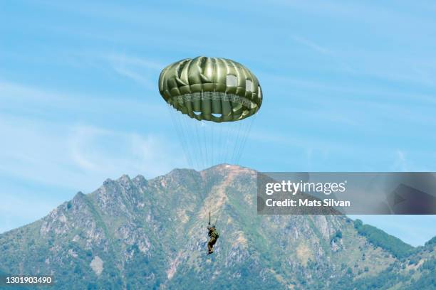 military skydiver with old parachute and mountain peak - paracaídas fotografías e imágenes de stock