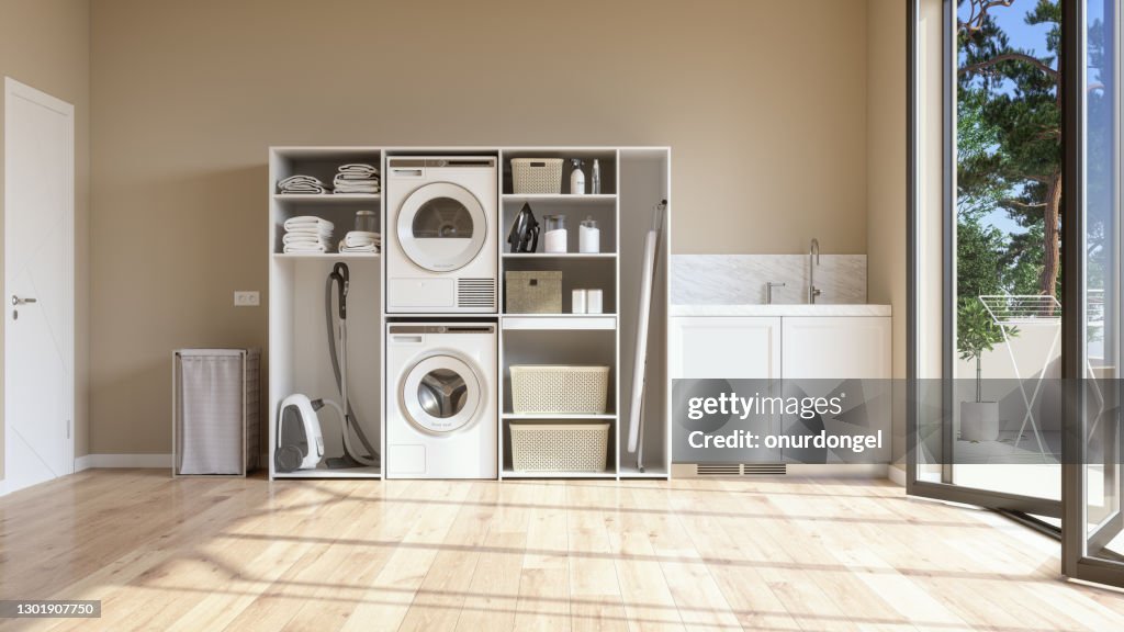 Laundry Room With Beige Wall And Parquet Floor With Washing Machine, Dryer, Laundry Basket And Folded Towels In The Cabinet.