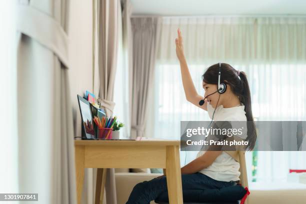 an asian teenage girl raises her hand, asks a teacher while studying online at a home living room during homeschooling while the school is closed due to the covid-19 outbreak. - english language bildbanksfoton och bilder