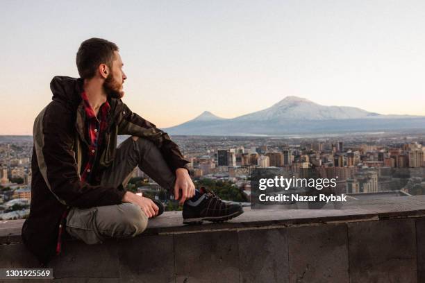 young man at the yerevan city and mount ararat background at the sunset in armenia - armenian culture stock pictures, royalty-free photos & images