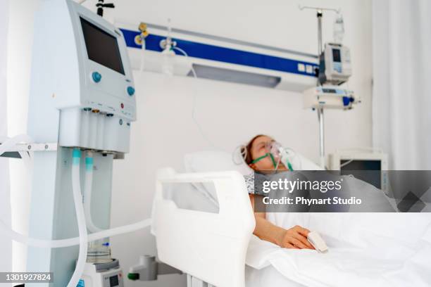 hospital covid patient with an oxygen mask lying down in bed - hospital ventilator stock pictures, royalty-free photos & images