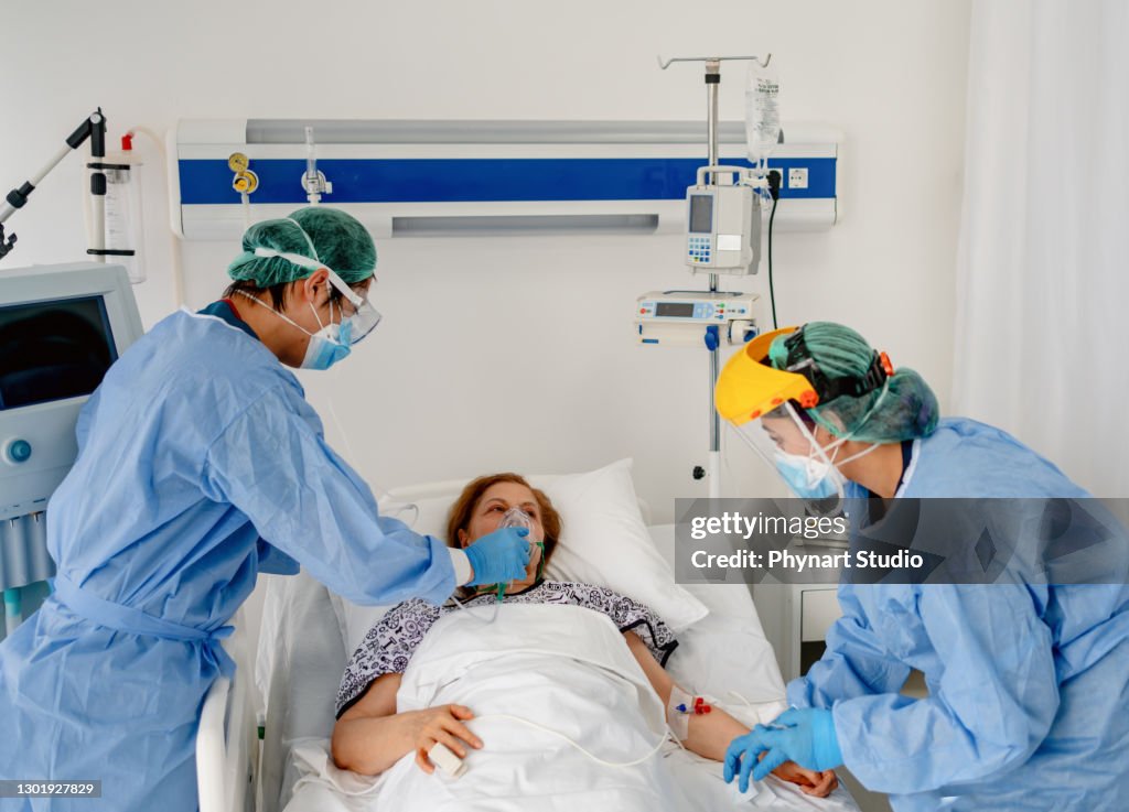 Healthcare team taking care of a COVID patient in PPE coveralls