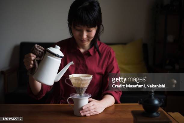 asiatische frau genießt ein kaffee-ritual zu hause - filterkaffee stock-fotos und bilder