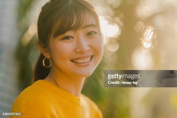 portrait of beautiful woman in yellow sweater in nature - japanese woman stock pictures, royalty-free photos & images