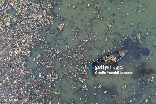 plastic pollution in the ocean; man cleaning plastic pollution in the sea - plastic waste stock-fotos und bilder