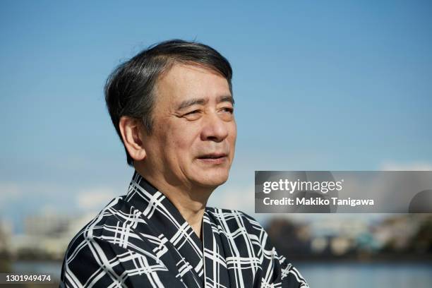 japanese senior actor standing by the river - japanese ol stockfoto's en -beelden