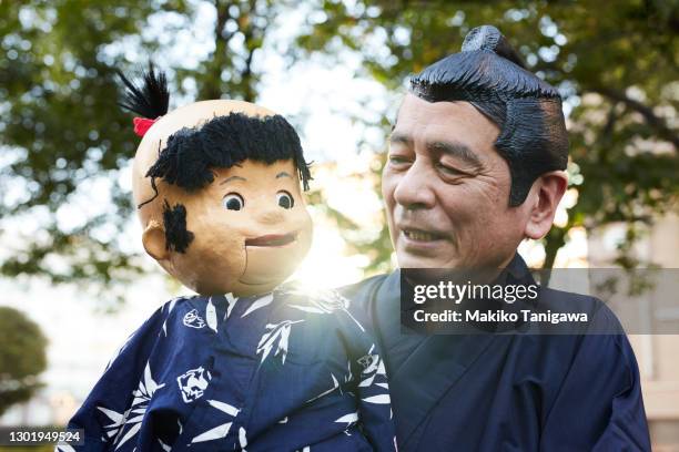 japanese senior comedian performing ventriloquism - sumo knot stockfoto's en -beelden