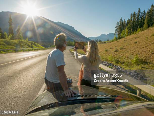 couple relax beside car, taking pic with digital tablet - sitting on top of car stock pictures, royalty-free photos & images