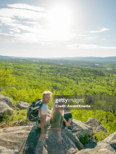 hiking couple relax on sunny mountain ridge - hiking mature man stock pictures, royalty-free photos & images