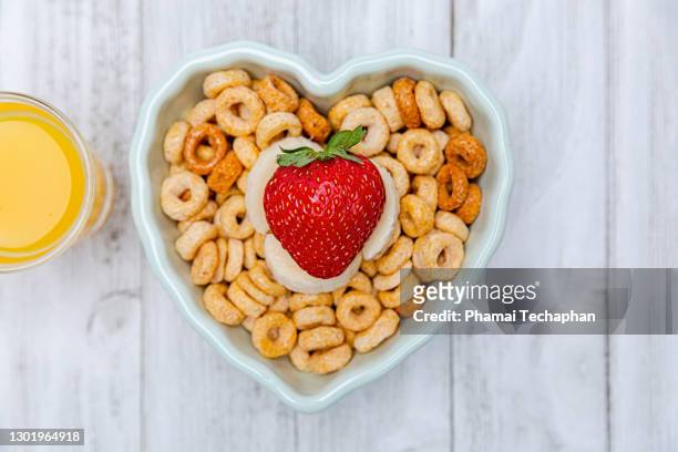cereal loops with a glass of orange juice - cheerios stock-fotos und bilder