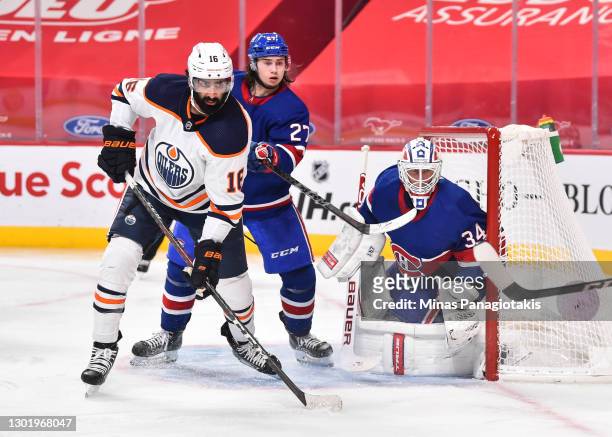 Jujhar Khaira of the Edmonton Oilers and Alexander Romanov of the Montreal Canadiens battle for position in front of goaltender Jake Allen during the...