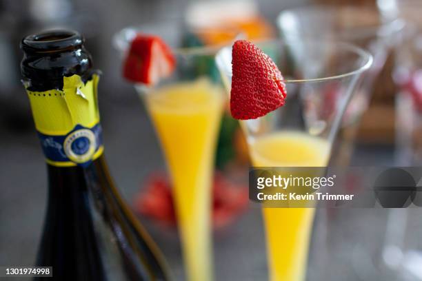 glasses full of mimosa's with strawberries on top and champagne bottle - champagne brunch stock pictures, royalty-free photos & images