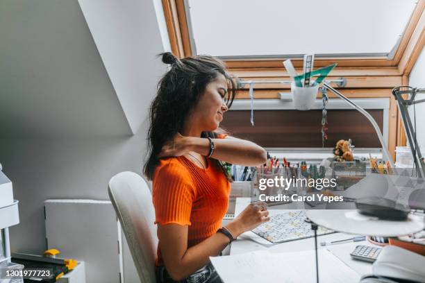 young female student with neck pain while sitting on desk preparing examns - burn out stock-fotos und bilder