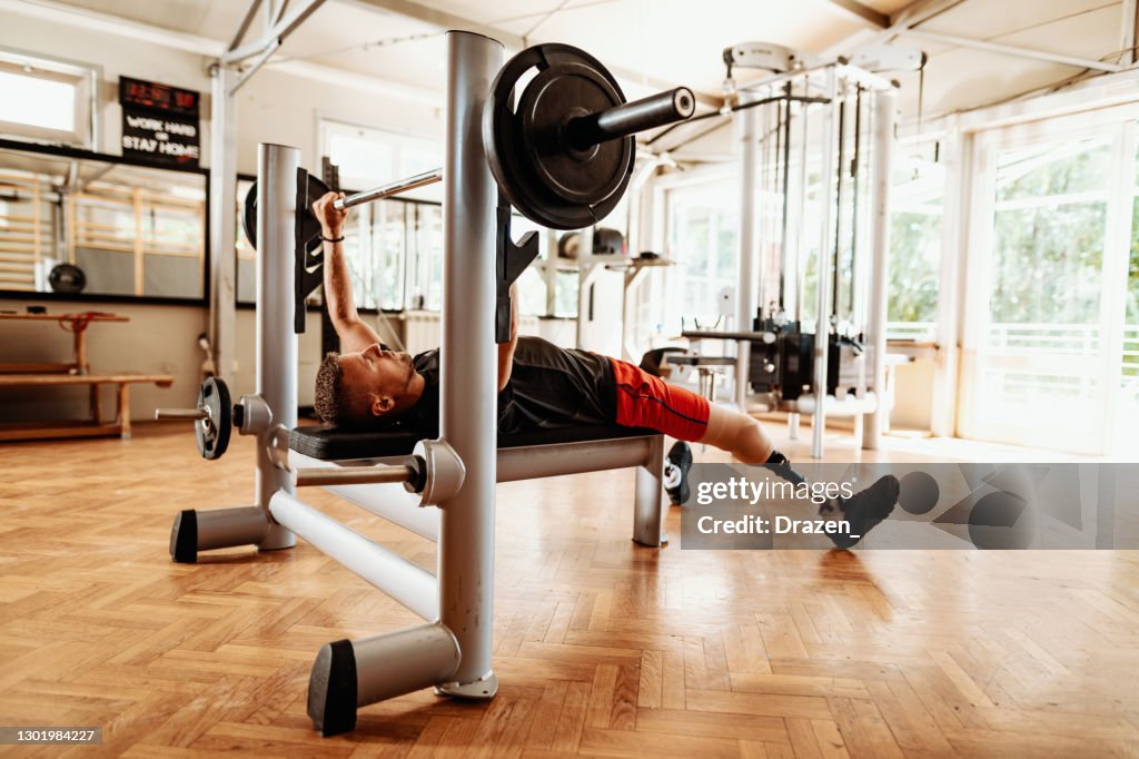 Amputee athlete exercising in the gym, benchpress workout