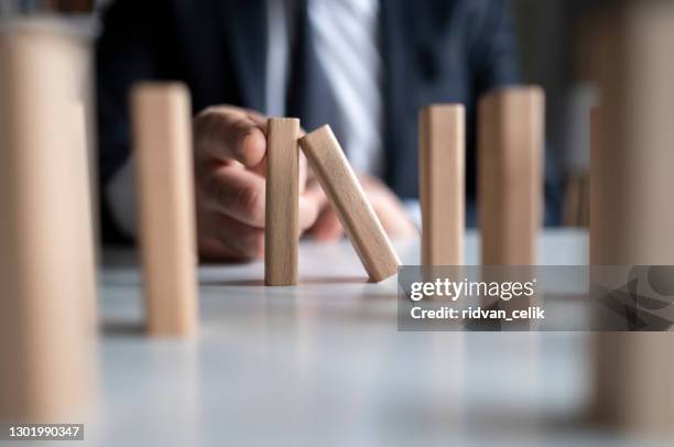 businessman stop domino effect. risk management and insurance concept - risk management stock pictures, royalty-free photos & images