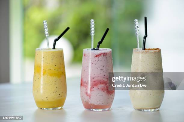 three smoothies on a table - batido de fresa fotografías e imágenes de stock