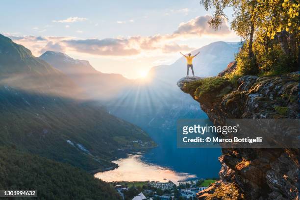hiker exulting from the top of geiranger fjord, norway - westelijke fjorden noorwegen stockfoto's en -beelden