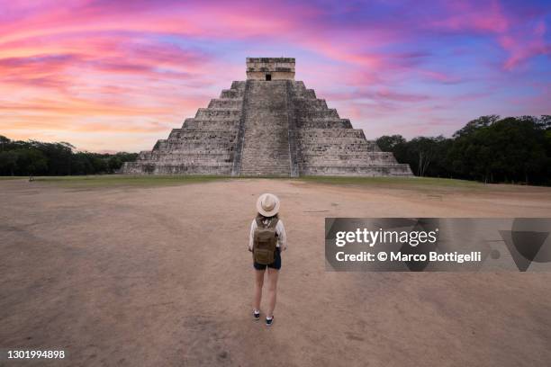 woman admiring chichen itza's kukulkan pyramid at sunrise, mexico - chichen itza stockfoto's en -beelden