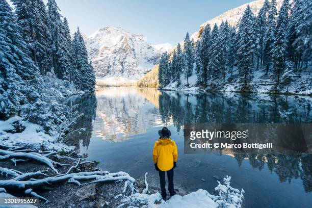 man admiring a mountain lake in winter scenery - frozen lake stock pictures, royalty-free photos & images