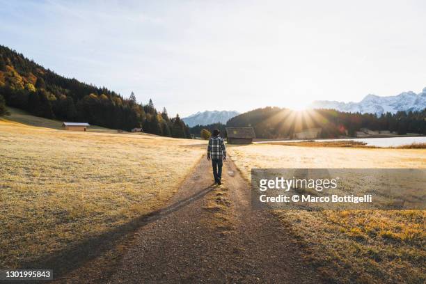 man walking along a pathway at geroldsee lake, germany - dirt road landscape sunset stock-fotos und bilder