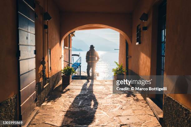 person walking on a narrow alley towards lake como, italy - como italia stock pictures, royalty-free photos & images