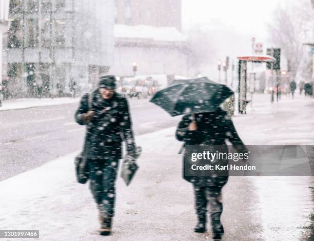 a view of two businessmen walking in snowy london - stock photo - weather improve in kashmir after two days of snowfall stockfoto's en -beelden