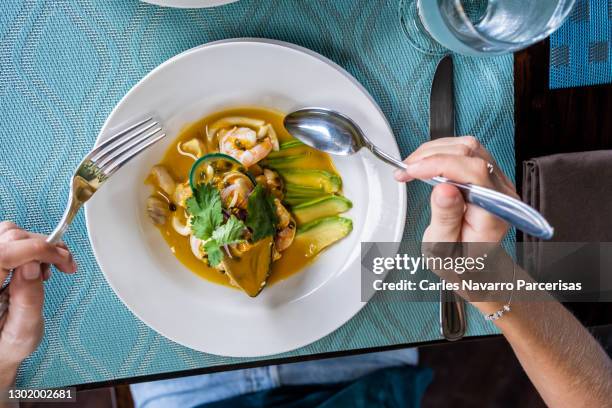 aerial photo of a person eating ceviche with a spoon and a fork in a restaurant - dining presentation food stock-fotos und bilder