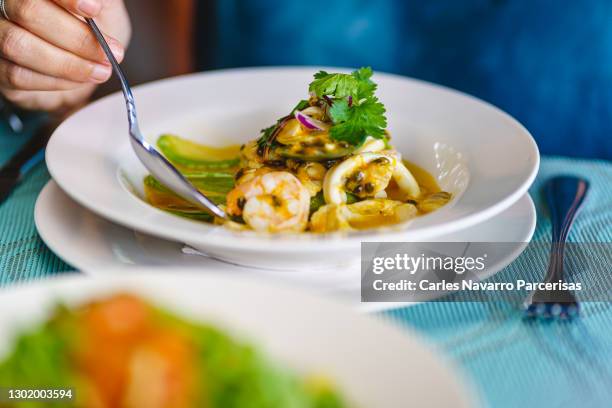 detail of the hands of a person eating ceviche with a spoon in a restaurant - dining presentation food imagens e fotografias de stock