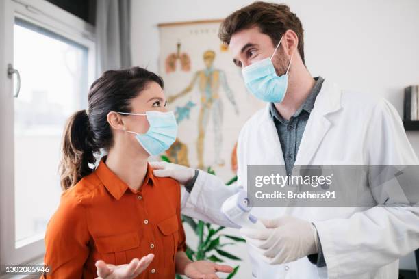 young caucasian woman being checked for temperature - protective face mask happy stock pictures, royalty-free photos & images