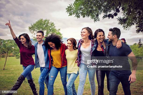 happy friends are walking ahead arm in arm - community arm in arm stock pictures, royalty-free photos & images