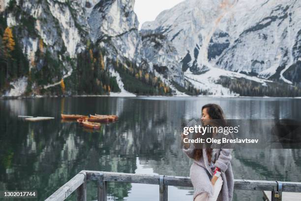 happy woman enjoying with glass of wine on background of lago di braies lake in winter - mountains alcohol snow bildbanksfoton och bilder