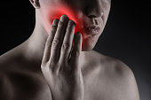 Man suffering from a toothache on black background, dentistry and periodontal disease concept