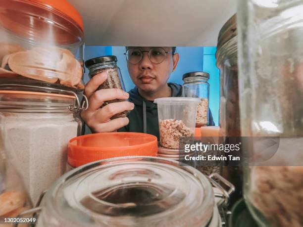 synvinkel asiatiska kinesiska manliga hämtar matflaska från hylla skåp vid kök - kitchen pantry bildbanksfoton och bilder