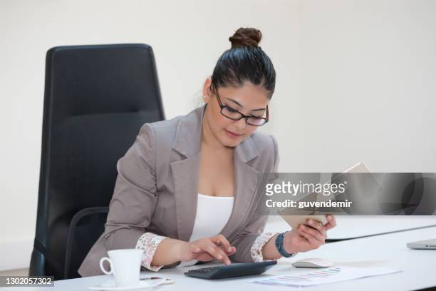 彼女のオフィスで電卓と金融について働くビジネスウーマン - 計算機ロールペーパー ストックフォトと画像