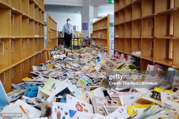 Staff stands in front of fallen books at Shinchi City Library a day after a magnitude 7.3 earthquake on February 14, 2021 in Shinchi, Fukushima,...