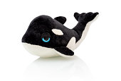 Killer whale plushie doll isolated on white background with shadow reflection. Plush stuffed orca  on white backdrop. Fluffy puppet toy for children. Cute furry plaything for kids. Black fish.