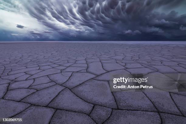 dramatic clouds over cracked soil in the desert. global warming concept. - hurricanes v heat stock-fotos und bilder