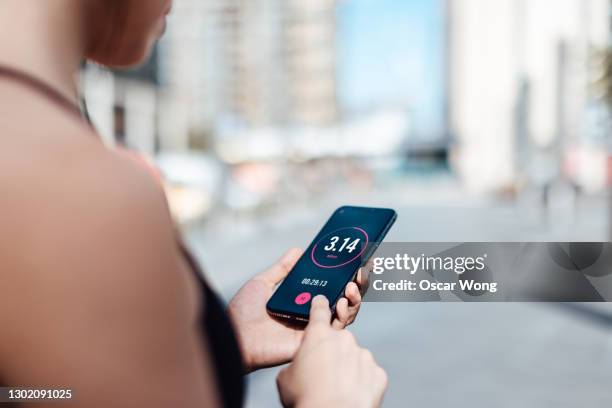 over the shoulder view of young active woman using exercise tracking app on smartphone to monitor her training progress after exercising at home - man over shoulder stock-fotos und bilder