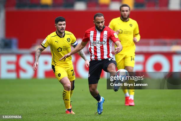 Brentford player Bryan Mbeumo beats Barnsley captain Alex Mowatt to the ball during the Sky Bet Championship match between Brentford and Barnsley at...