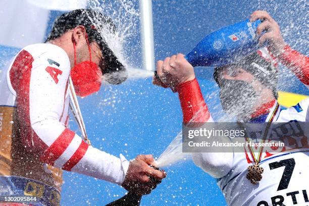 3rd place finisher Beat Feuz of Switzerland sprays 1st place finisher Vincent Kriechmayr of Austria with Champagne on the podium during the FIS World...