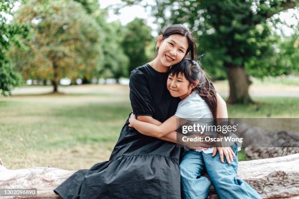 young mother hugging her daughter in park - chinese mothers day foto e immagini stock