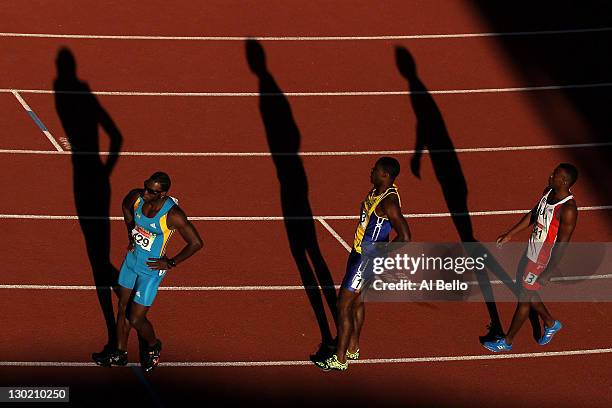 Jamial St. John Rolle of the Bahamas, Ramon Gittens of Barbados and David Lescay of Cuba stand on the track after competing in the men's 100m...