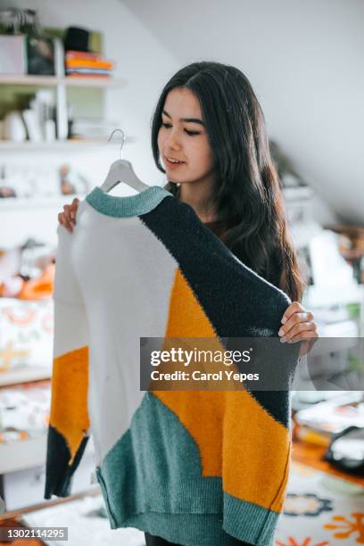 young latina woman choosing a sweater from her closet - trying on stock-fotos und bilder