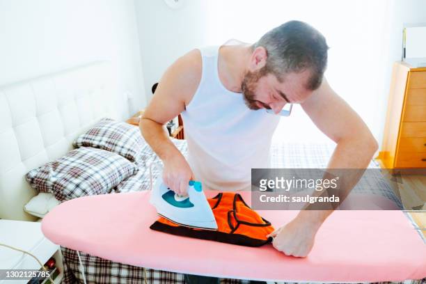 man ironing underwear while talking on the phone - bügelbrett stock-fotos und bilder