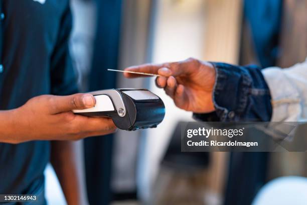 ein filialkaufmann streckt seine hand aus, damit der kunde bei der kontaktaufnahme mit seinem kauf über ein datentelefon bezahlen kann. - poes stock-fotos und bilder