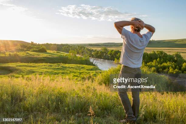 man stretches on prairie meadow and river, sunrise - alberta prairie stock pictures, royalty-free photos & images
