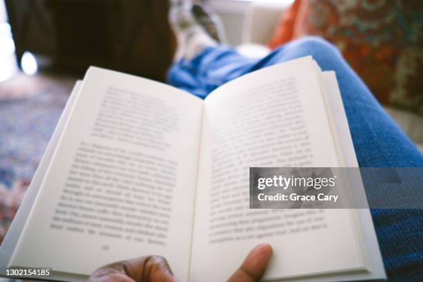 woman reads book on sofa - book hand stock pictures, royalty-free photos & images