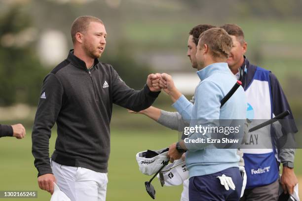 Daniel Berger of the United States fist bumps Russell Knox of Scotland and Patrick Cantlay of the United States on the 18th green after winning...