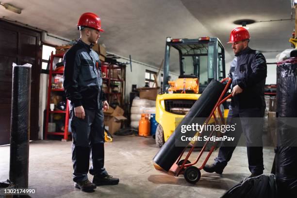 two males workers moving rolled rubber in a warehouse - rubber material stock pictures, royalty-free photos & images