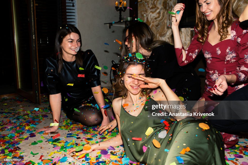 Group of friends having fun with confetti at home.